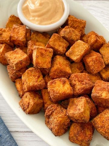 air fryer tofu on white serving dish with dipping sauce.