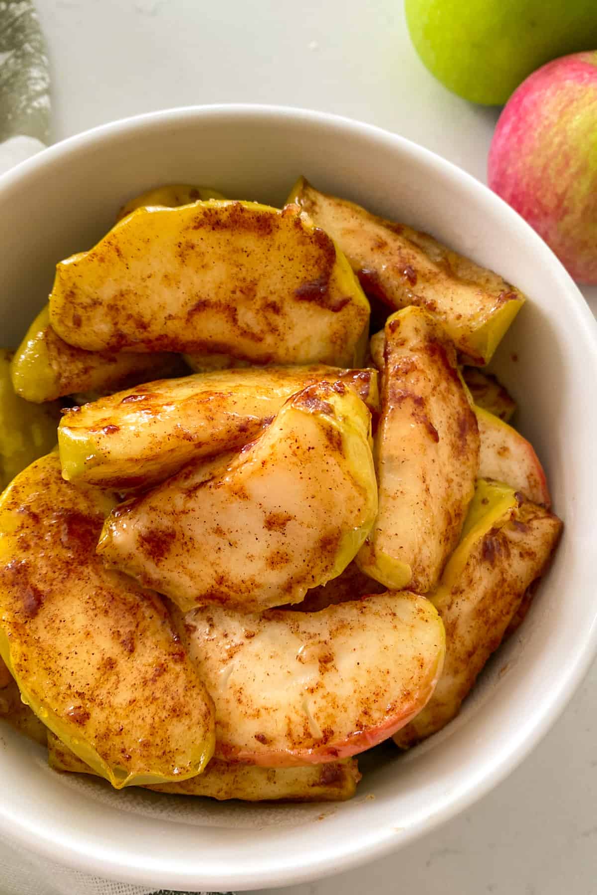Close up of baked apples in white serving dish.