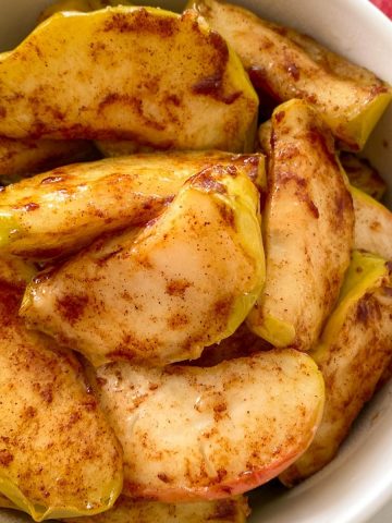 Close up of baked apples in white serving dish.