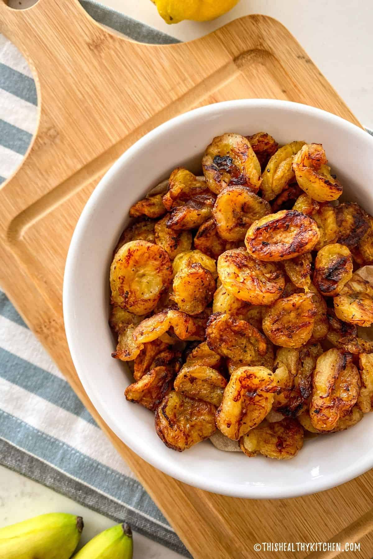 Air fried banana chips in white bowl.
