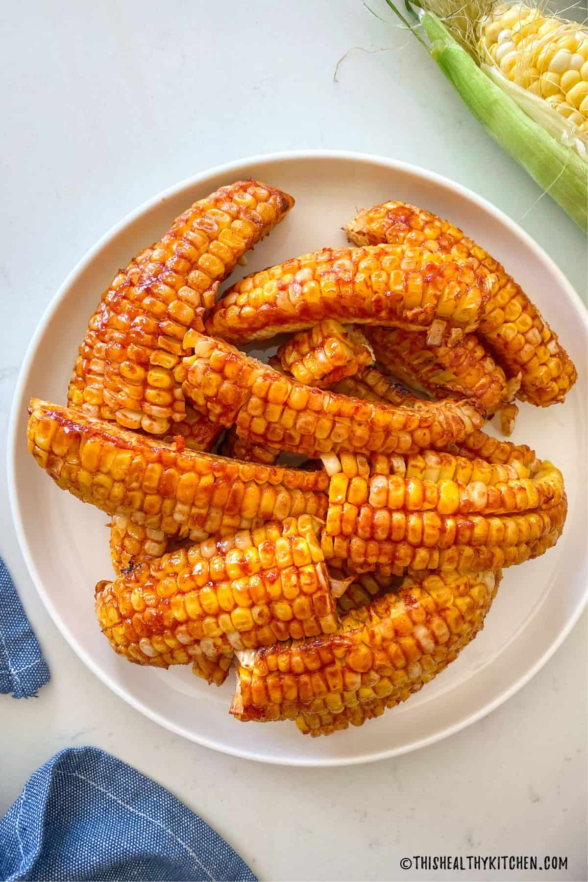 Air fried corn ribs with bbq sauce on top in white plate.