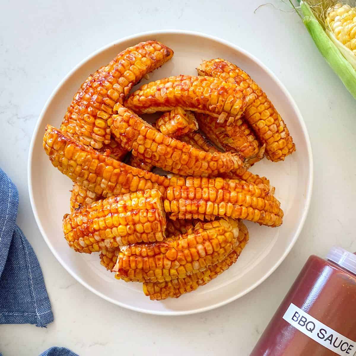 Air fried corn ribs with bbq sauce on top in white plate.
