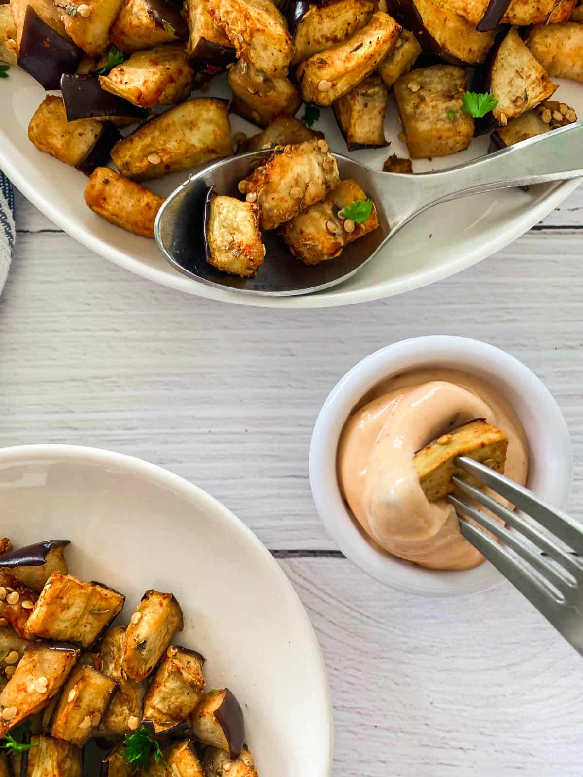 Fork with eggplant piece on it, being dipped into spicy mayo.