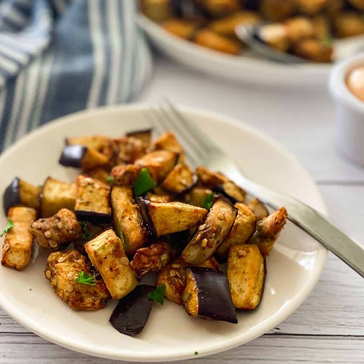 Plate of diced air fried eggplant with fork on the side.