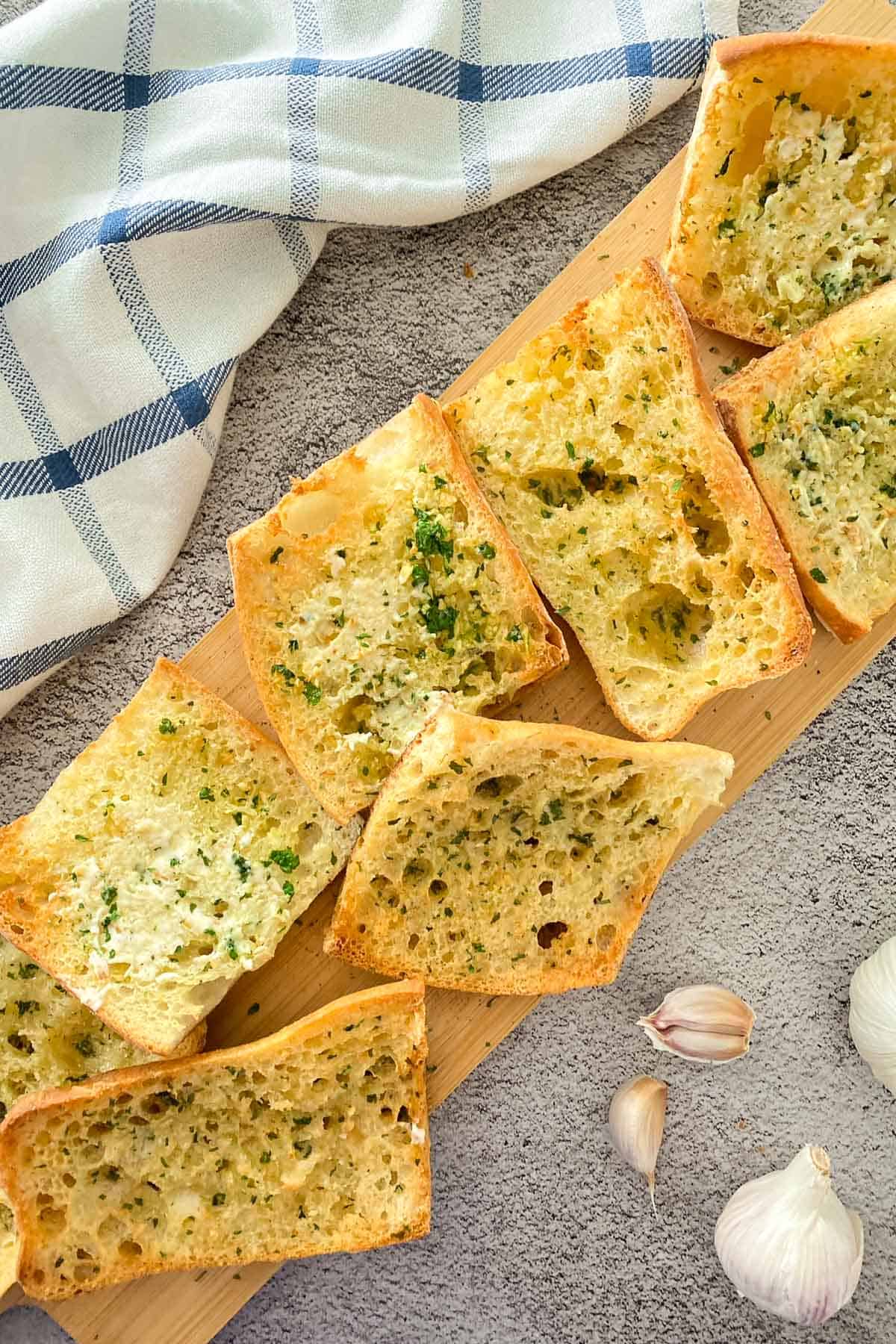 Slices of garlic bread on wooden cutting board.