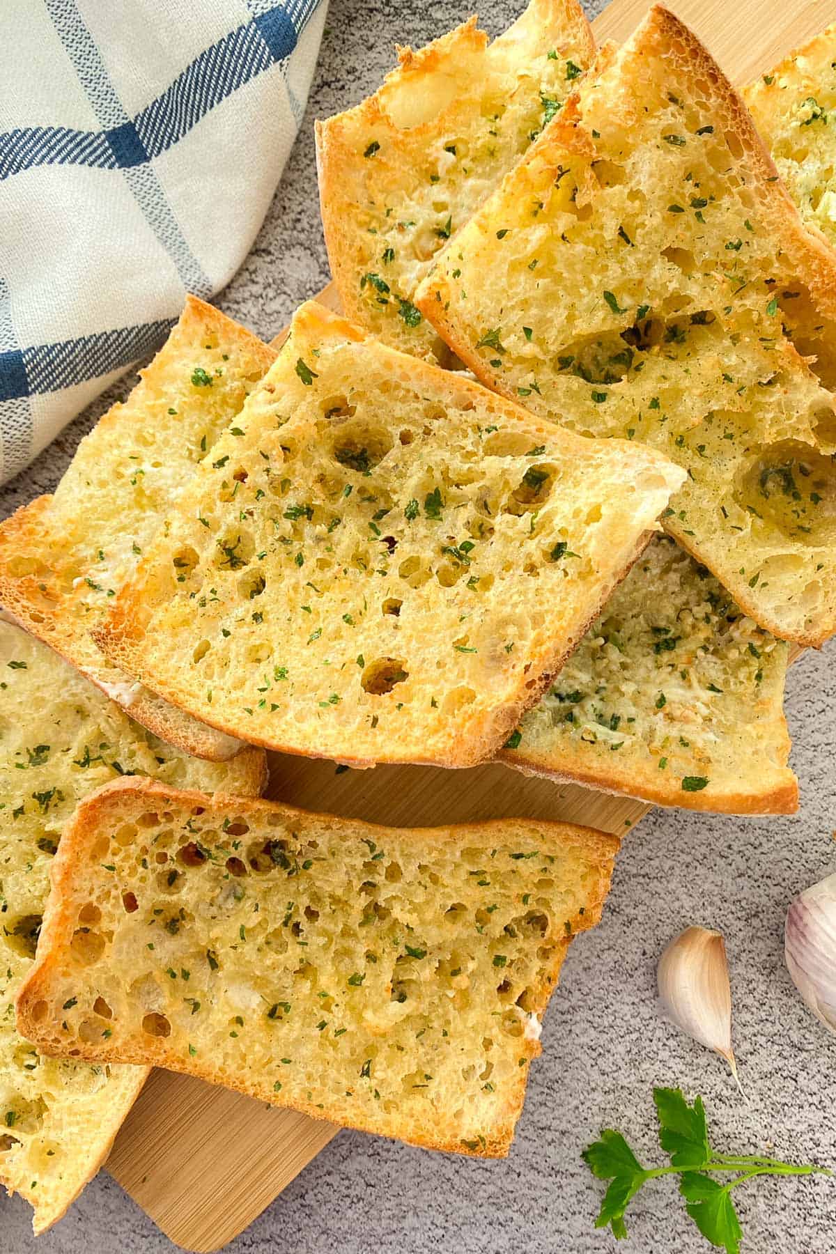Crunchy garlic bread on cutting board with parsley garnish.
