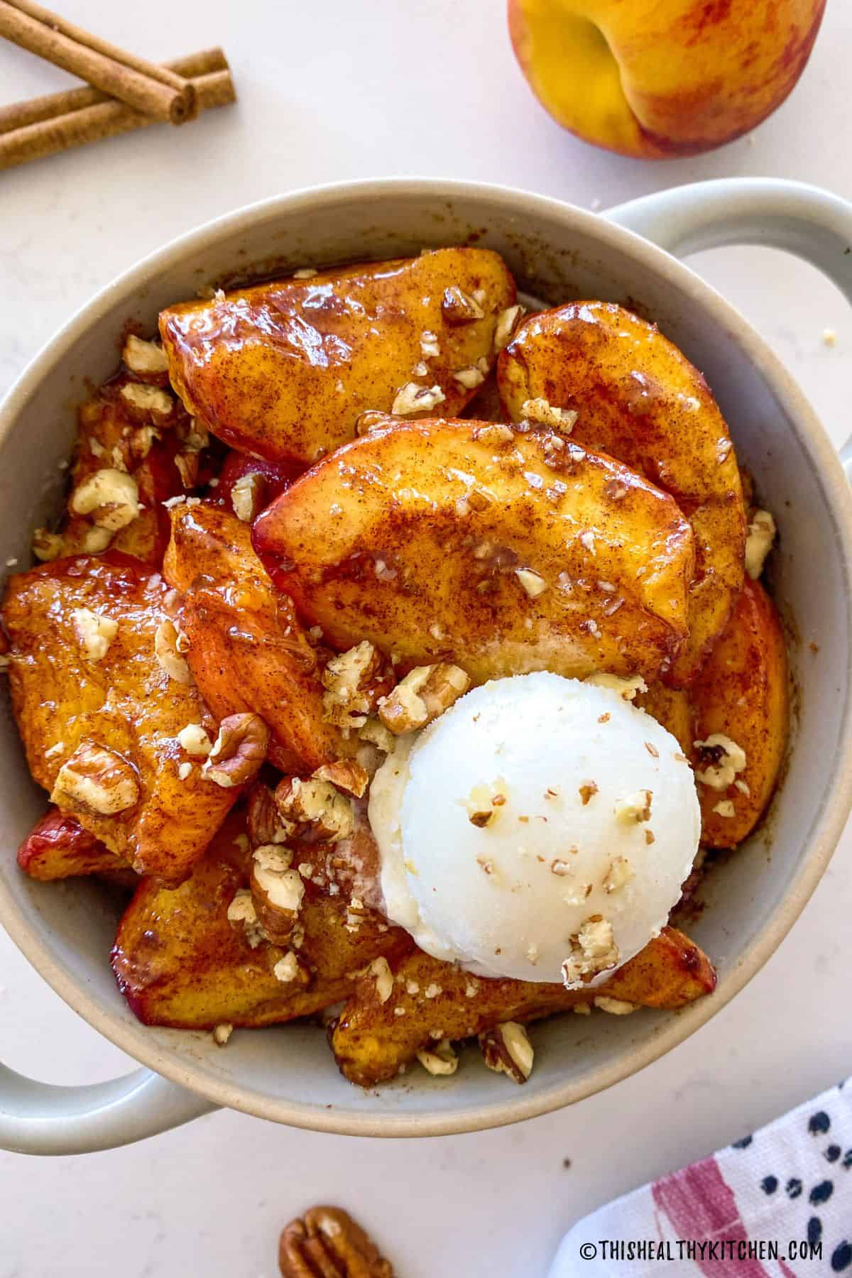 Baked peaches with chopped pecans and a scoop of vanilla nice cream on top.