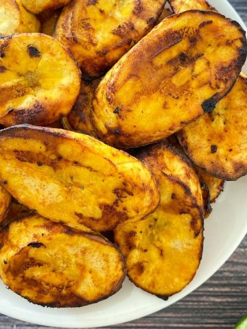 White plate with air fried plantain chips inside.