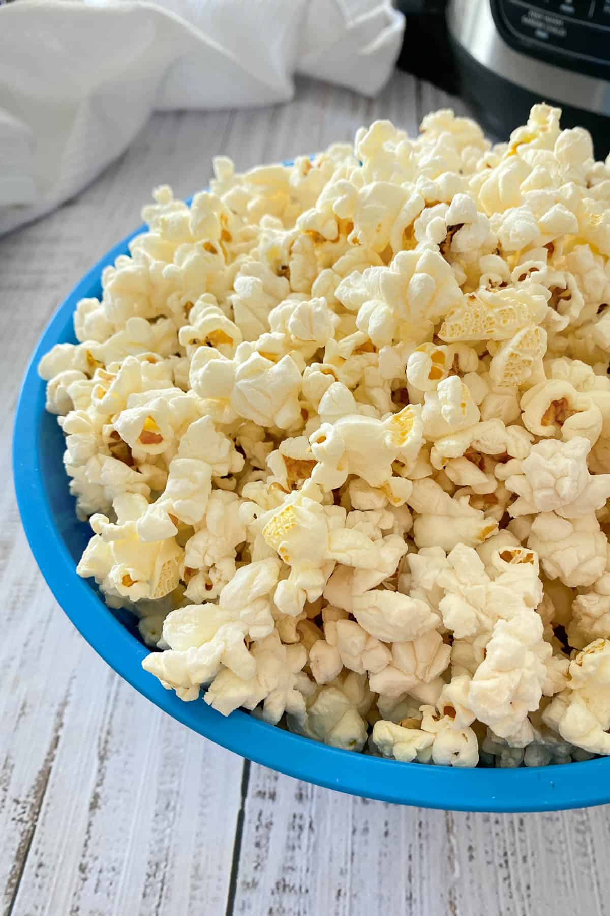 Big bowl of popcorn on white deck.