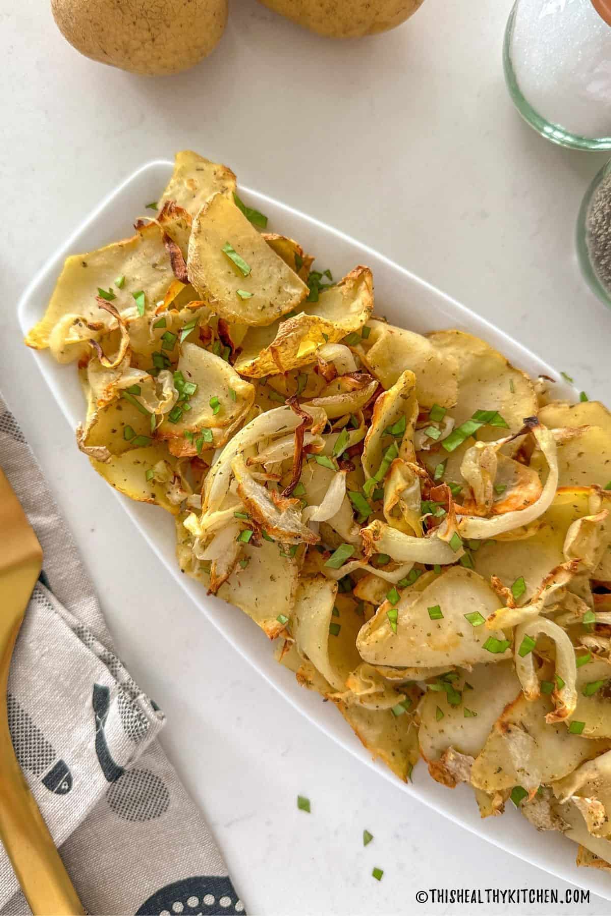 Air fried onions and potatoes in white serving dish.
