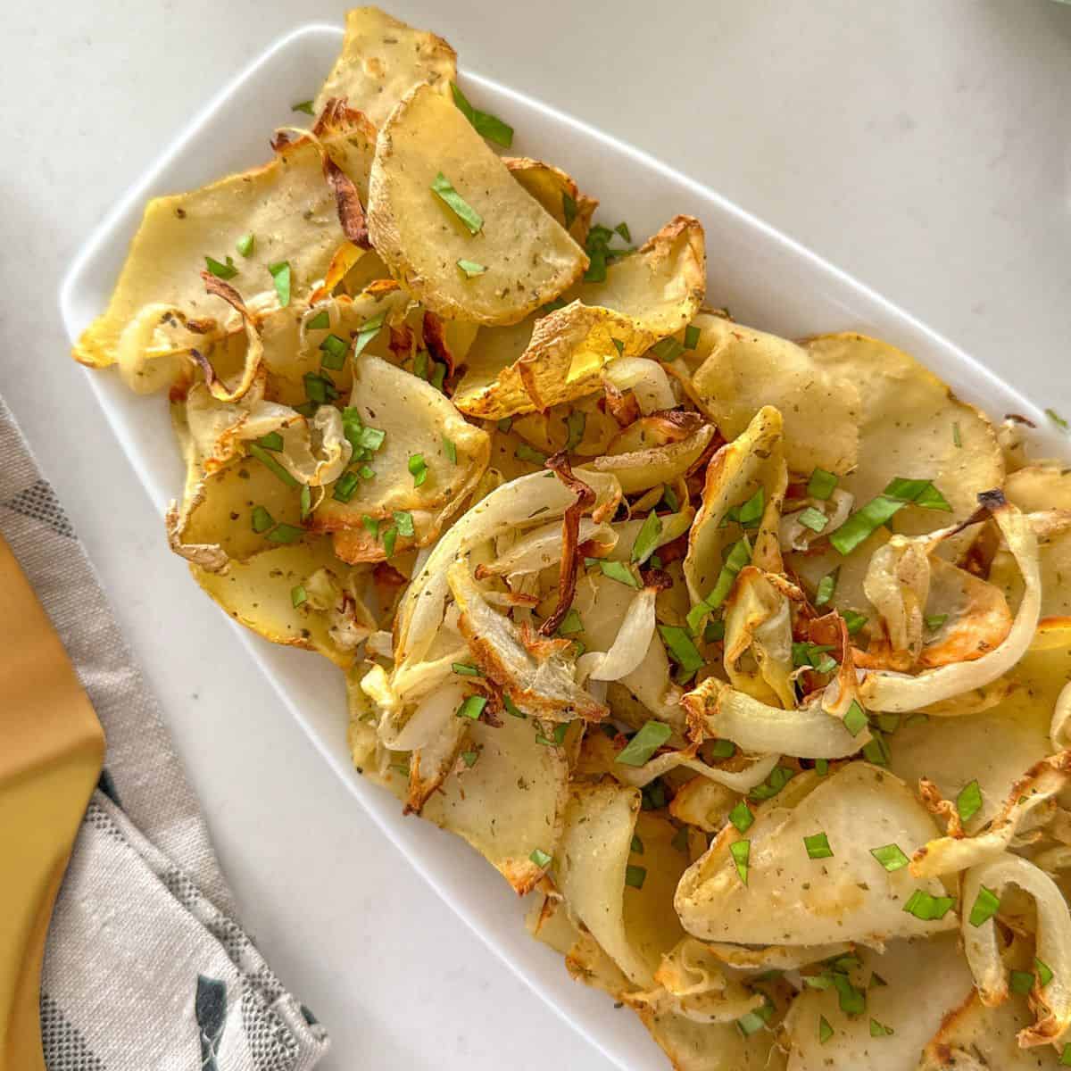 Air fried onions and potatoes in white serving dish.