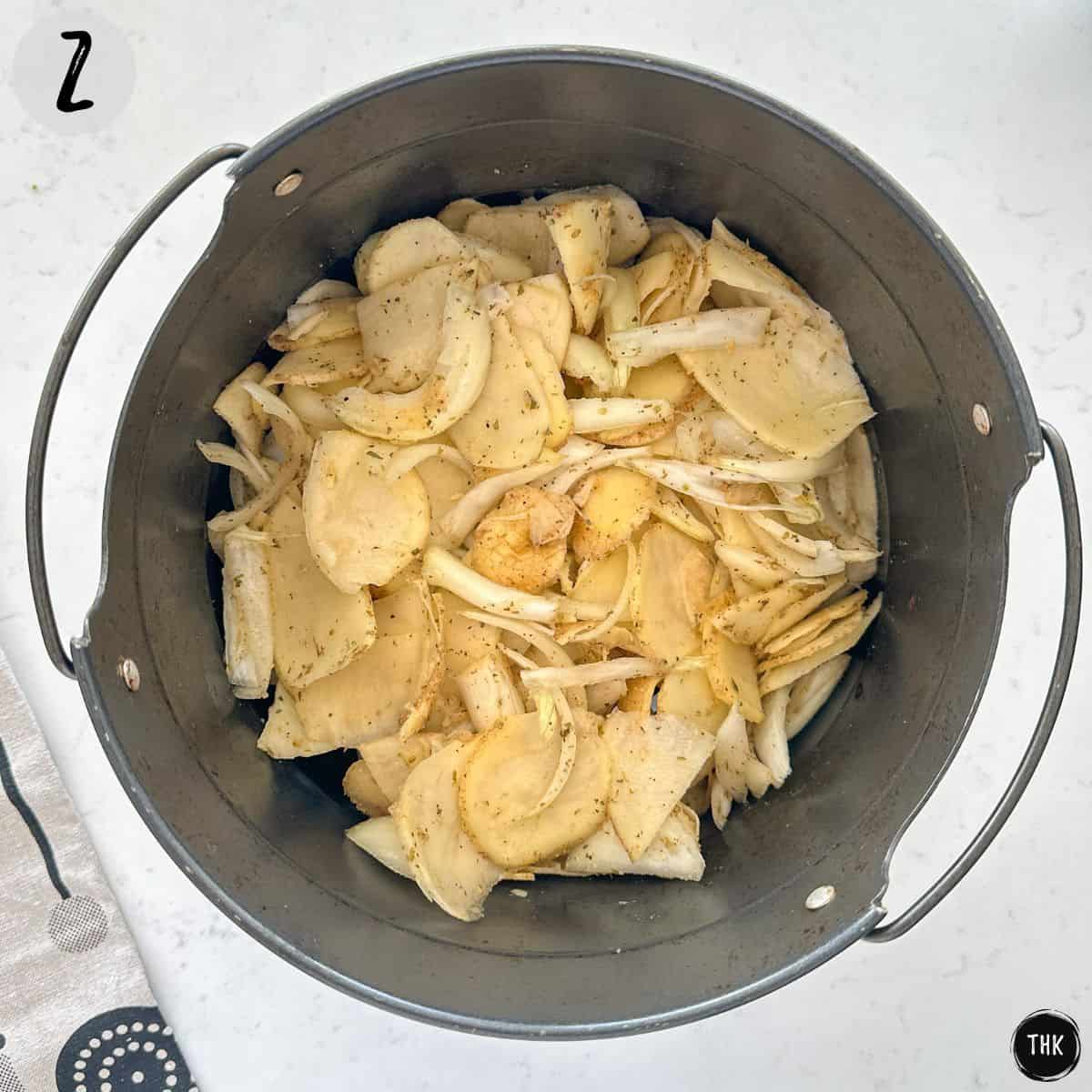 Raw onions and potatoes inside air fryer basket.