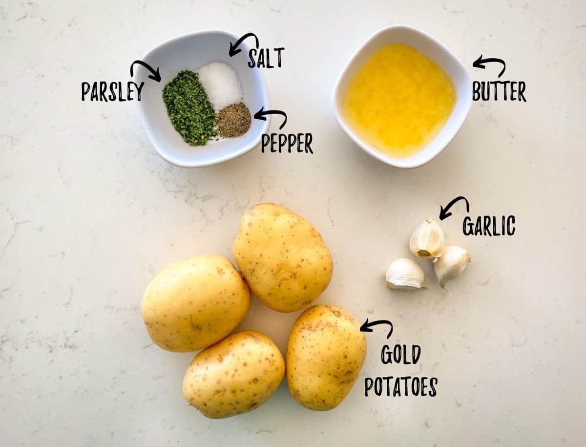Potatoes, butter, garlic and seasoning scattered on kitchen counter.