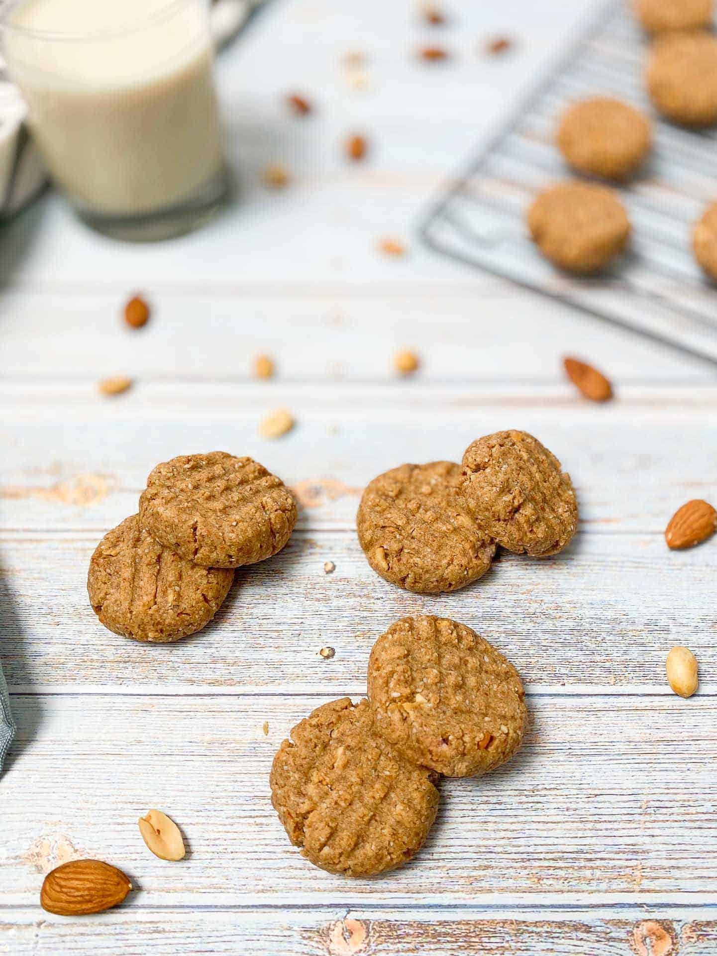 peanut butter almond cookies scattered on deck with glass of milk in background