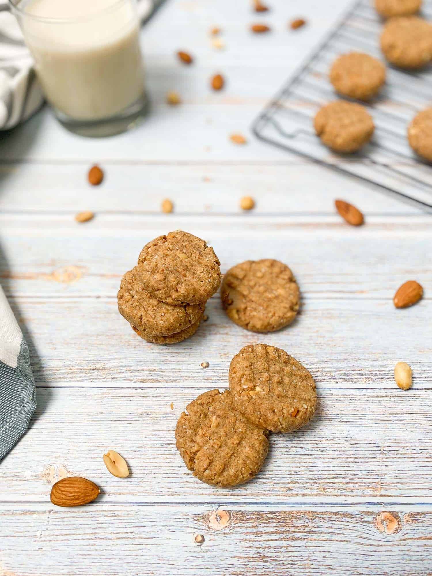 peanut butter almond cookies scattered on deck with peanuts and almonds around them