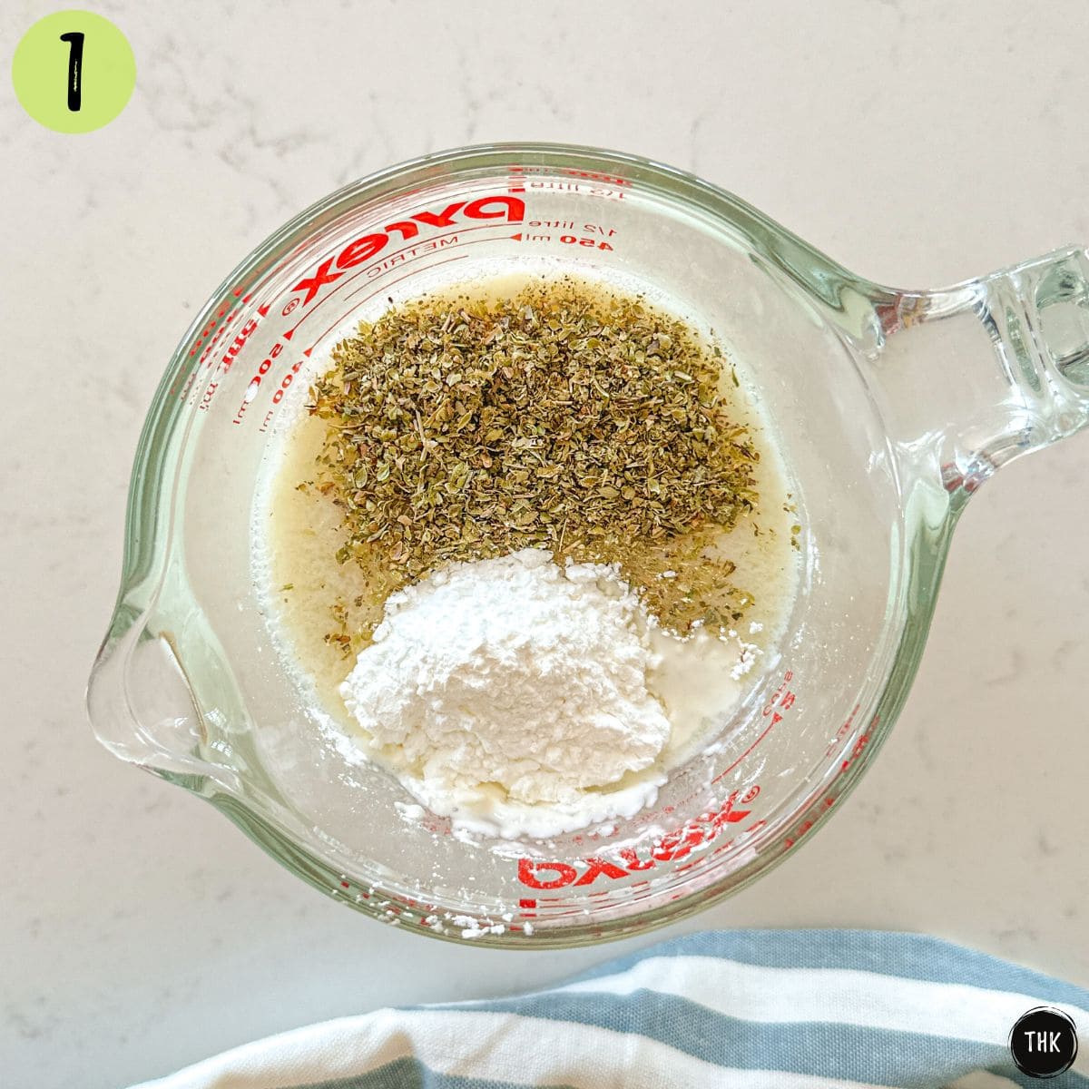 Measuring cup with broth, milk, spices, and cornstarch inside.