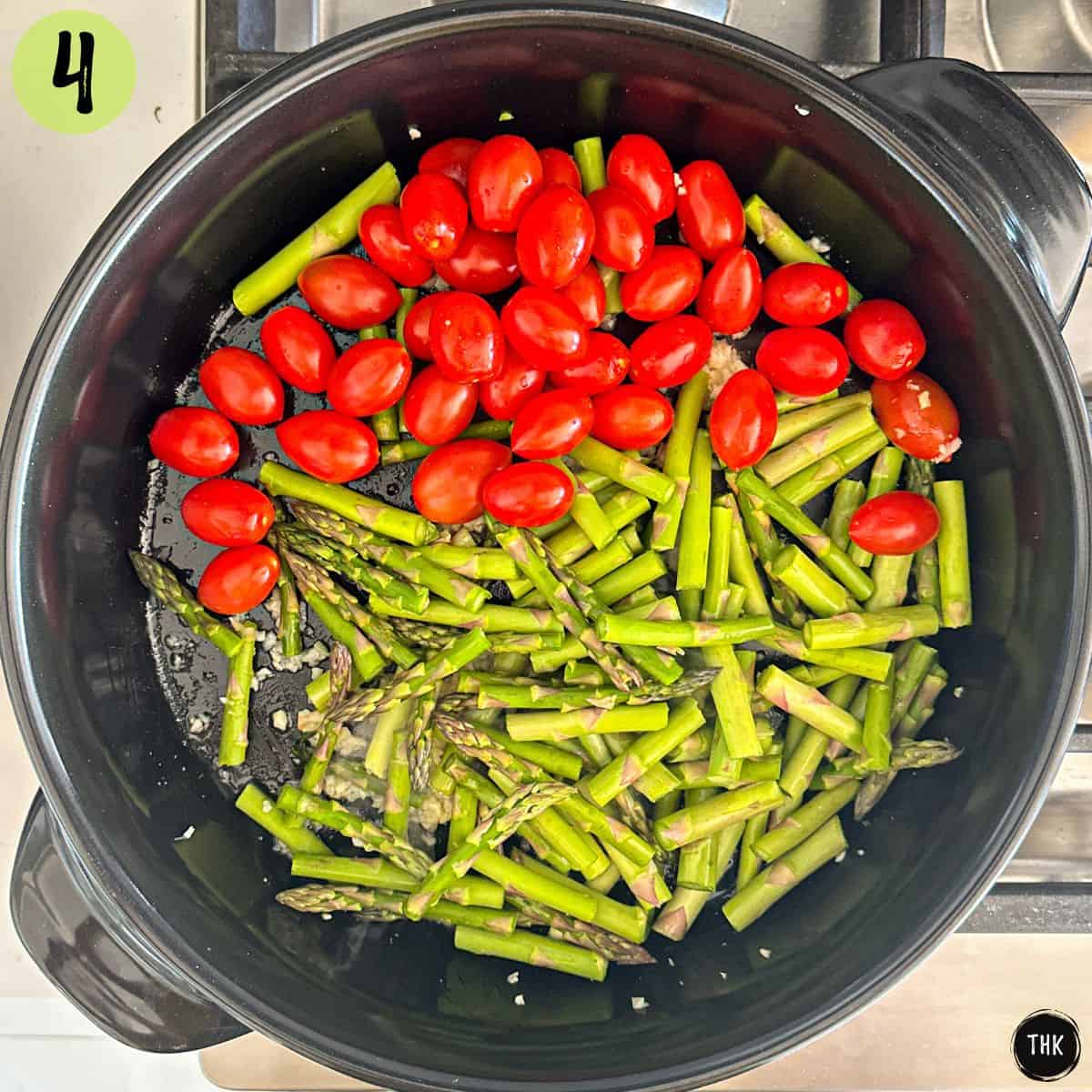 Large skillet with cherry tomatoes and asparagus inside.