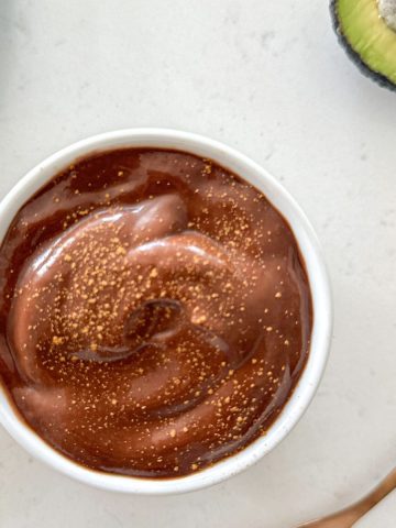 White bowl of chocolate mousse with cinnamon sprinkled on top.