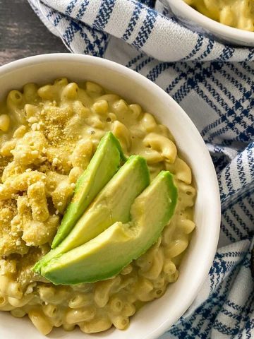 Mac and cheese in bowl with avocado slices on top.