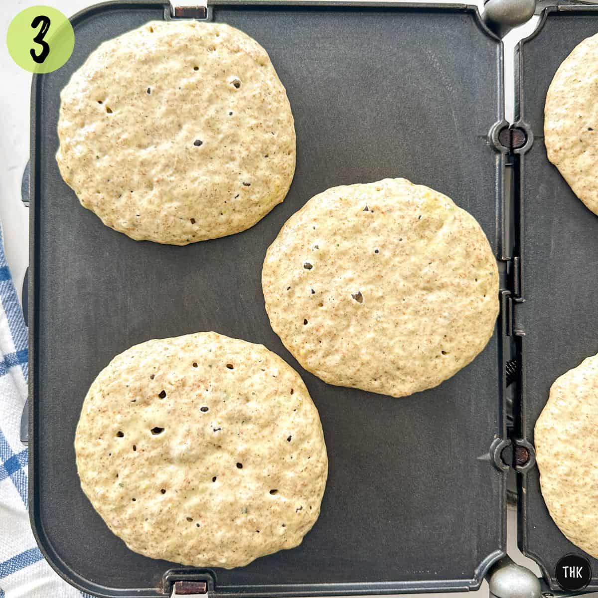 Pancakes cooking on griddle.