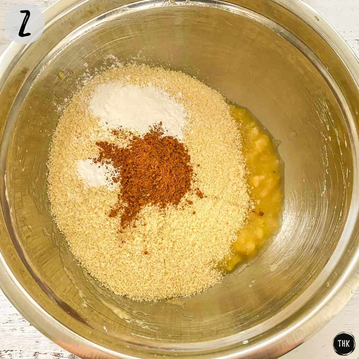 Mashed banana, flour, cinnamon and baking powder inside large mixing bowl.