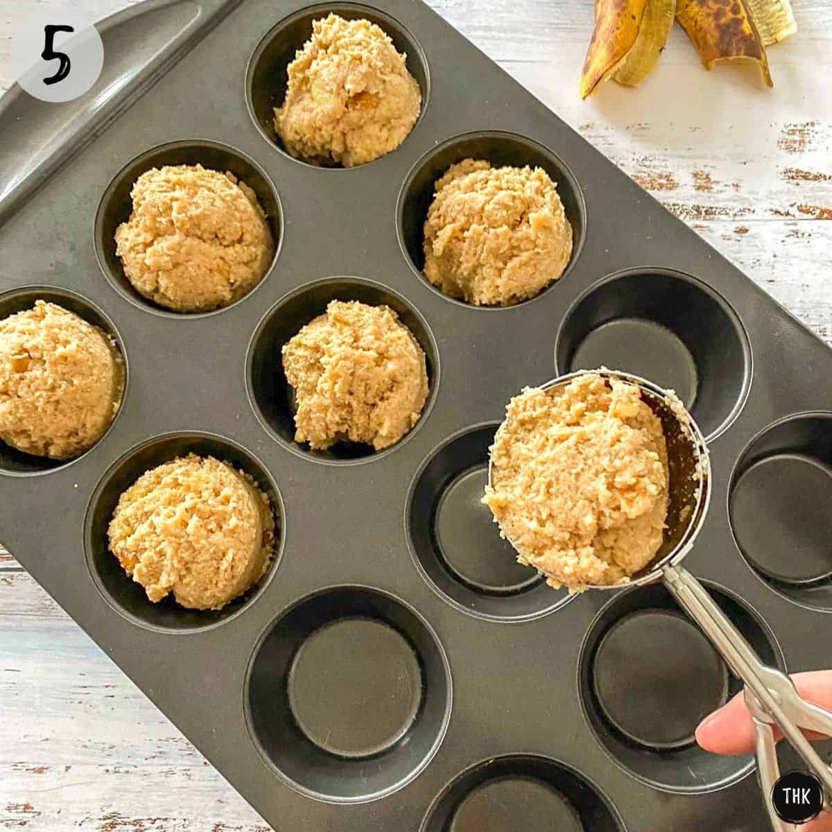 Scoop of batter being transferred into muffin pan.