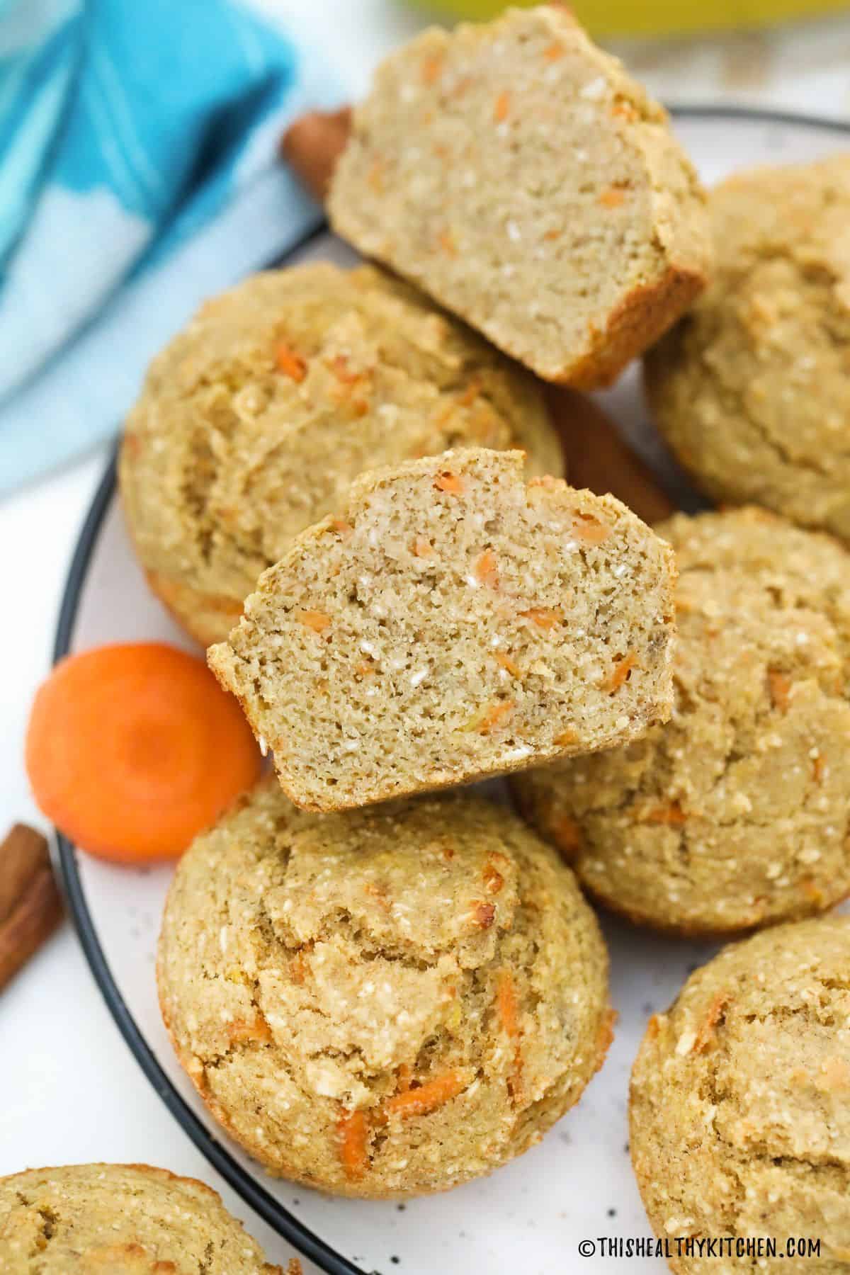 Carrot muffins on plate with one of them cut in half.