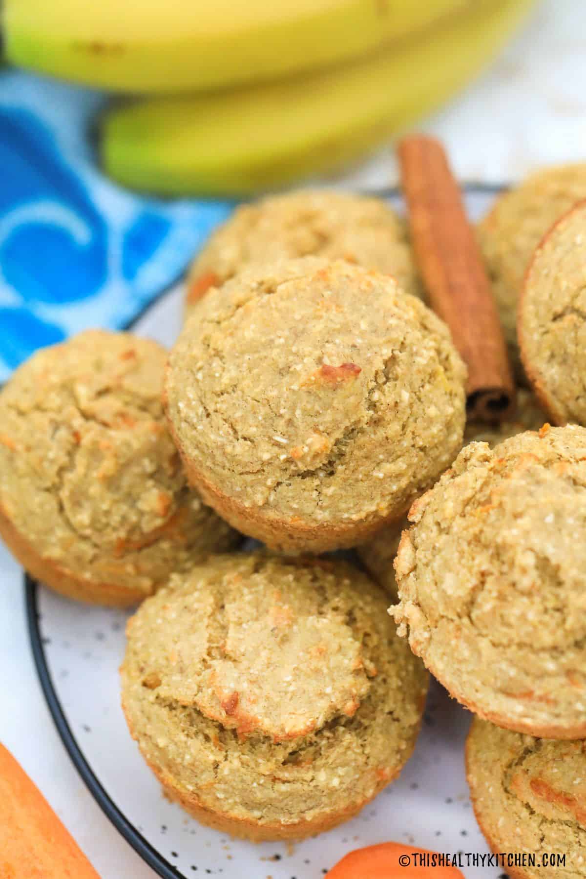 Carrot muffins on plate with cinnamon stick on top.