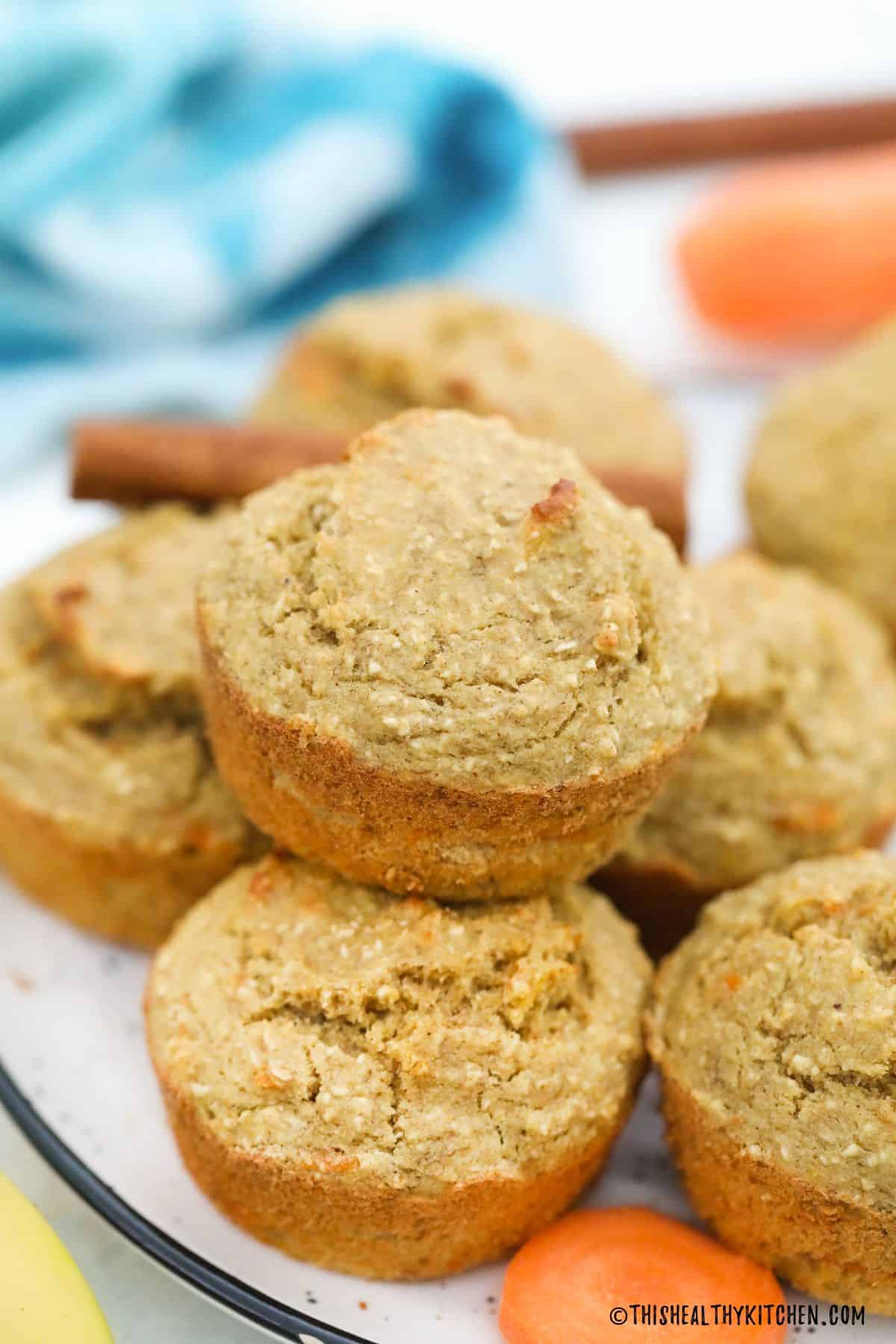 Banana carrot muffins on plate with carrot slice in front.