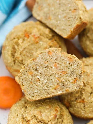Carrot muffin sliced in half with more muffins below it.