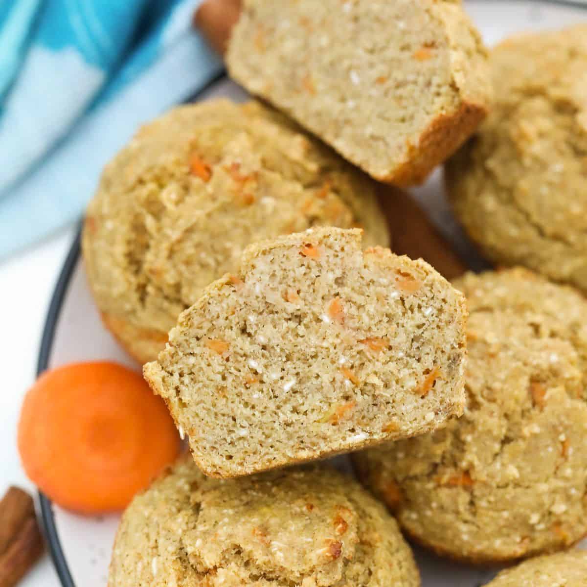 Carrot muffin sliced in half with more muffins below it.