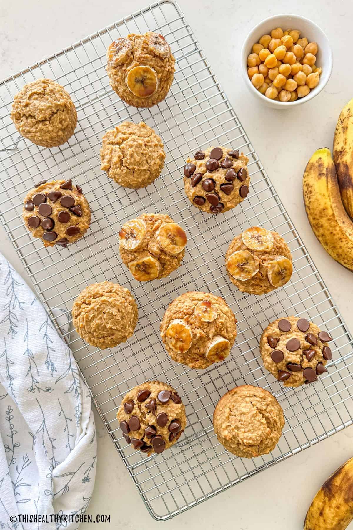 Chickpea muffins on cooling rack with some of them studded with banana slices or chocolate chips.
