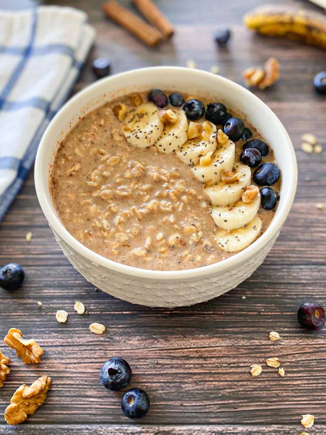 Side view of bowl of overnight oats with banana slices and blueberries on top.