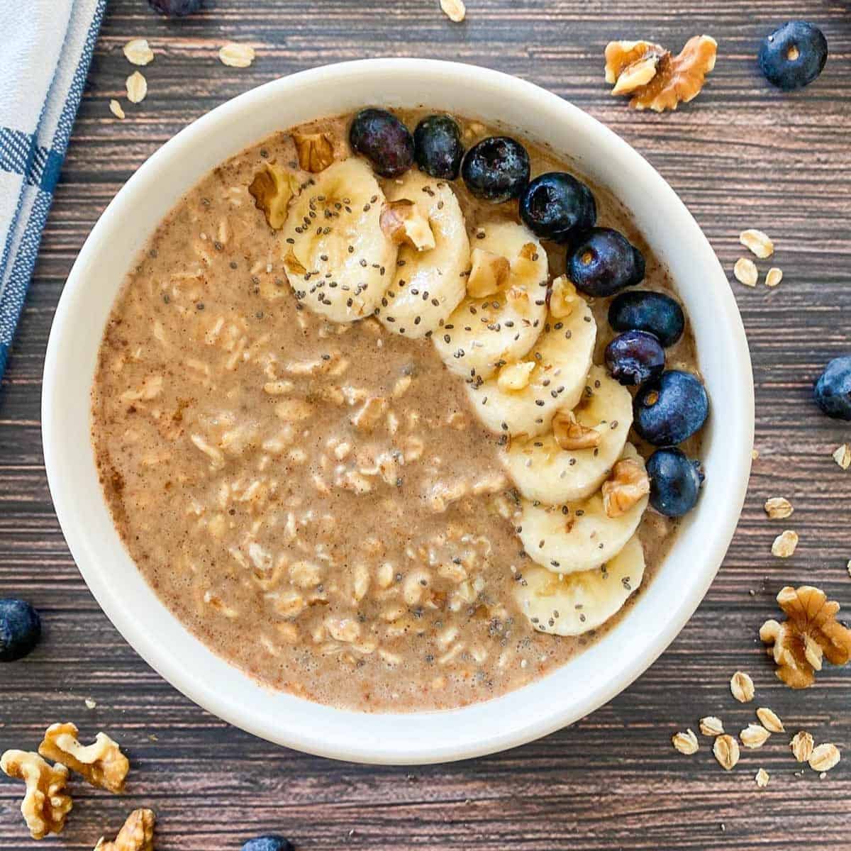 Bowl of oatmeal with banana slices, walnuts, blueberries and chia seed garnish.