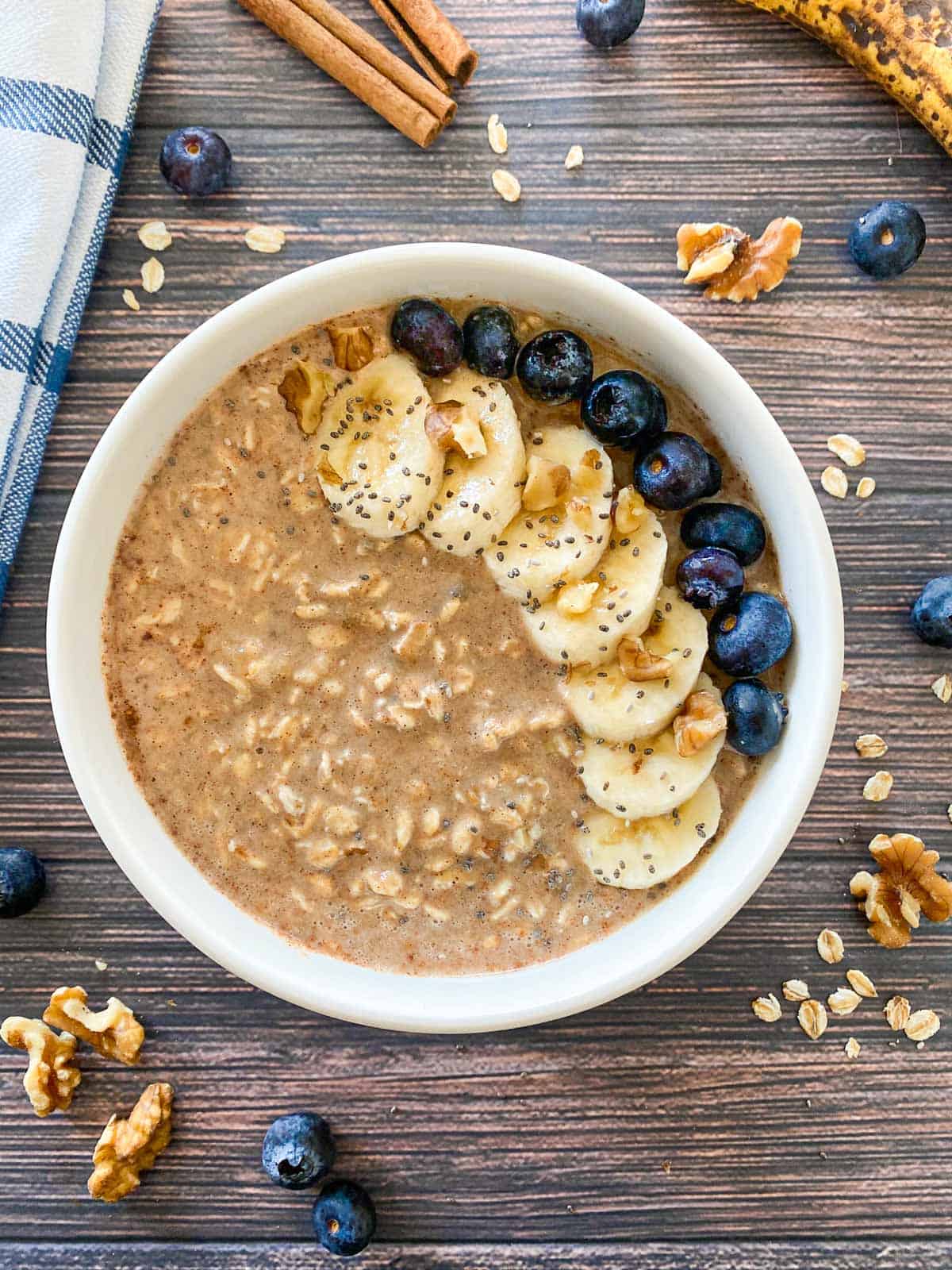 Bowl of oatmeal with banana slices, walnuts, blueberries and chia seed garnish.