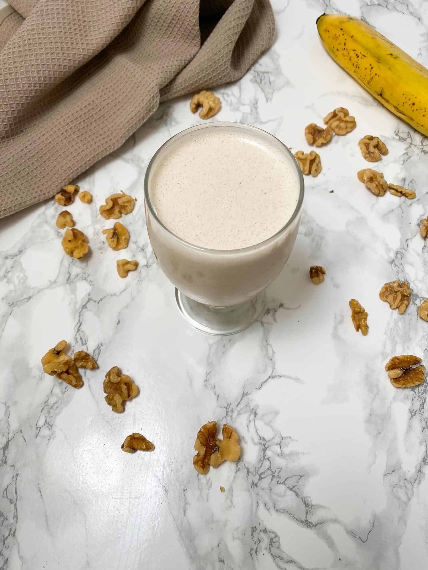 glass filled with white beverage sitting on marble counter