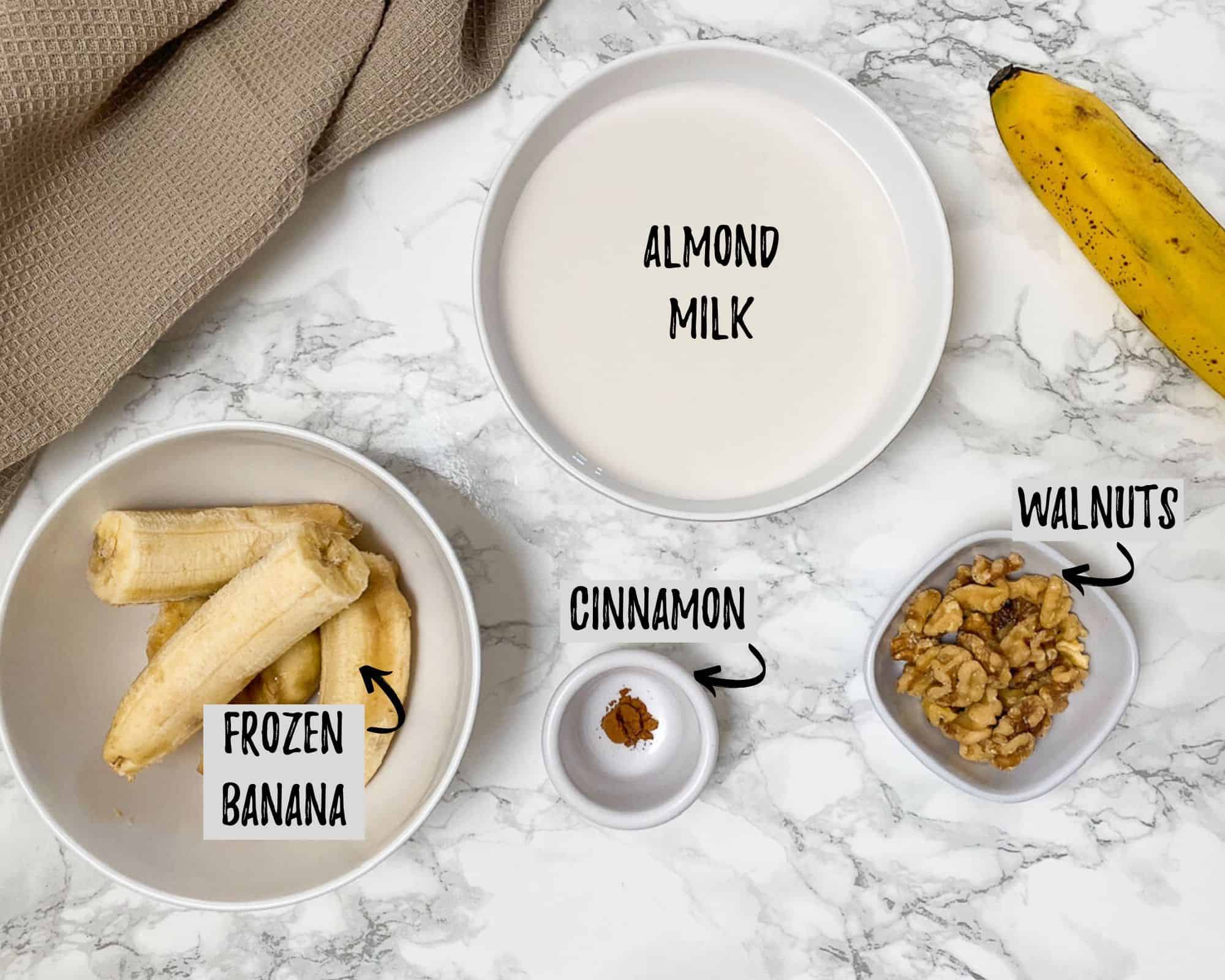 bowl of milk, bowl of frozen bananas, bowl of walnuts and cup of cinnamon on kitchen counter
