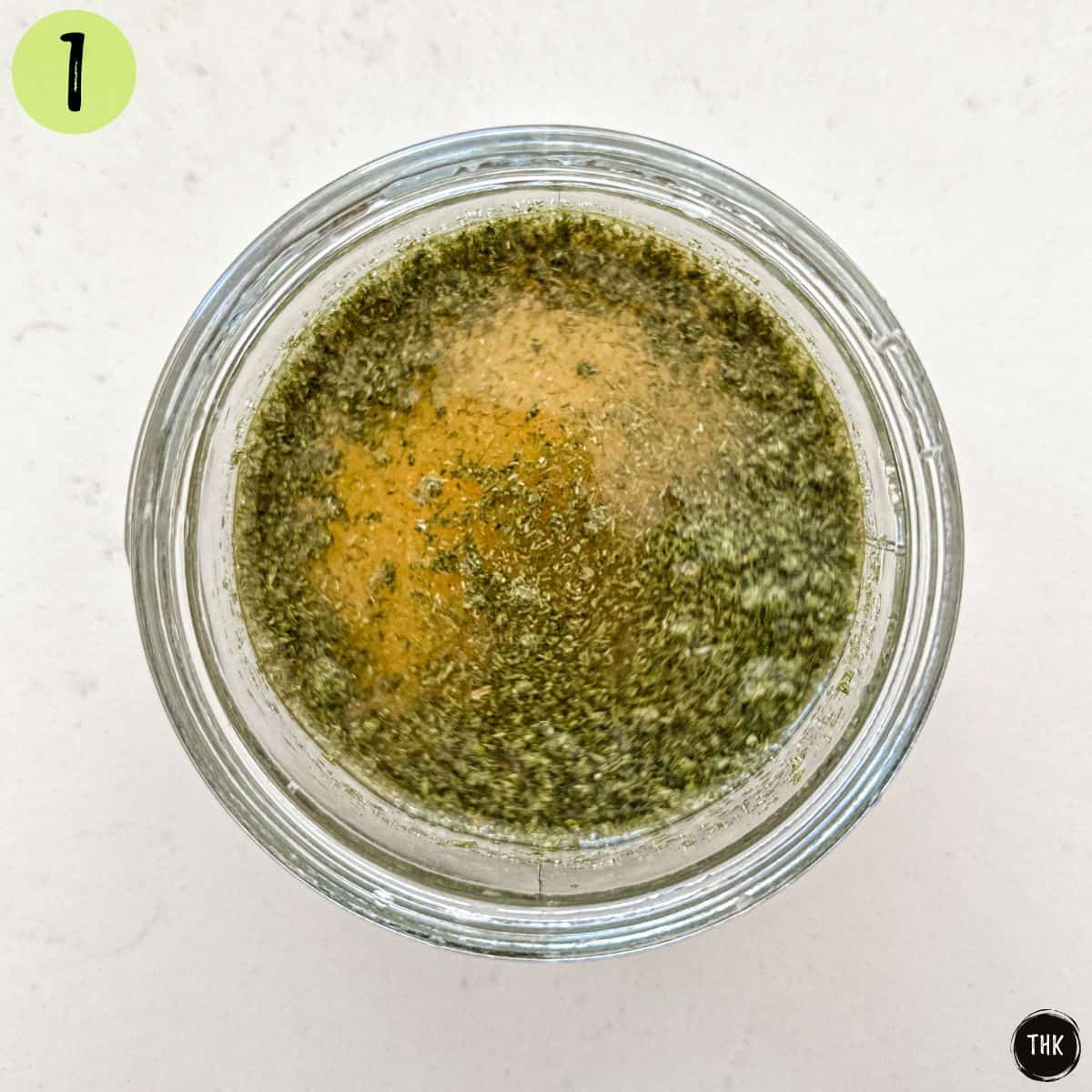 Lemon based salad dressing in small glass jar.