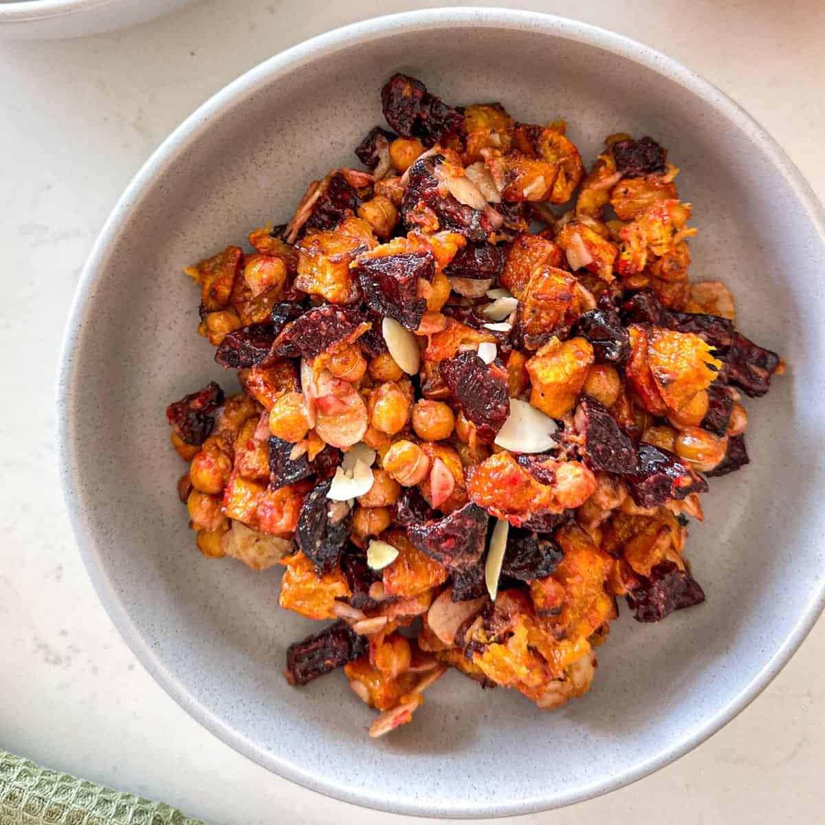 Grey bowl with beet and pumpkin salad with chickpeas, slivered almonds and cranberries.