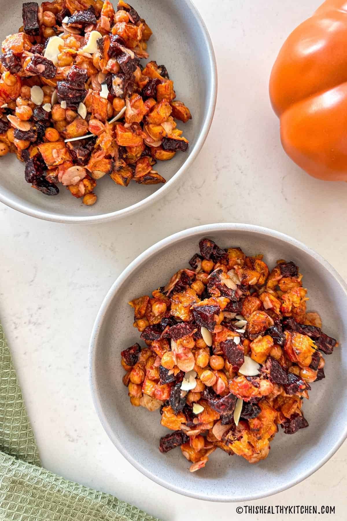 Two bowls of beet and pumpkin salad with chickpeas, slivered almonds and cranberries.