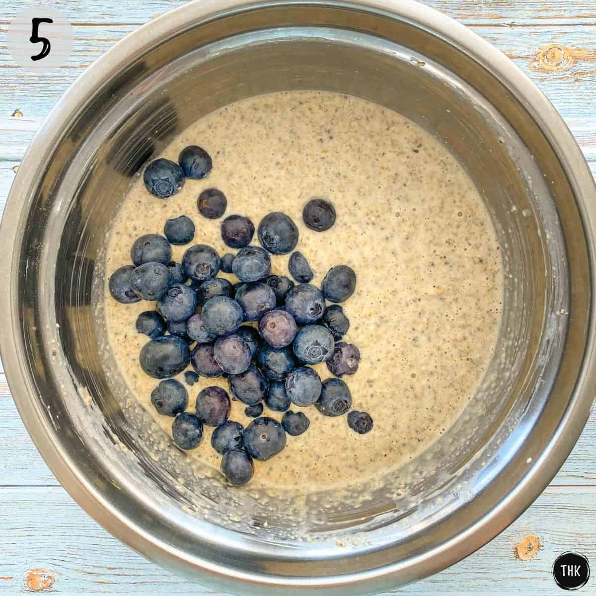 Pancake batter inside mixing bowl with blueberries on top.