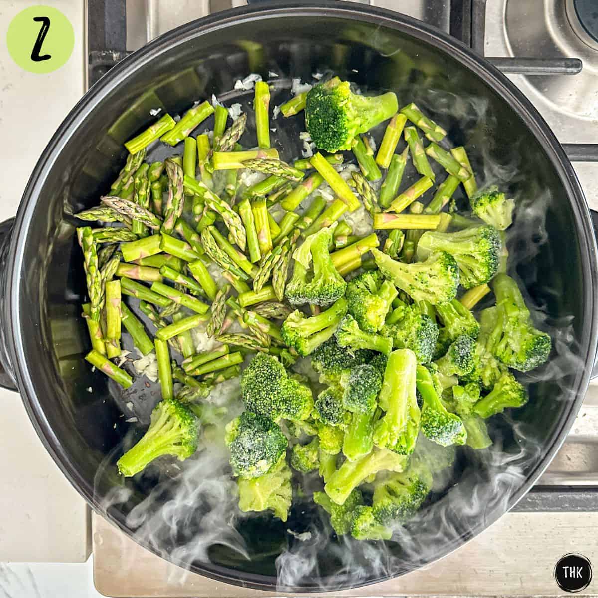Chopped asparagus and broccoli florets inside large skillet.