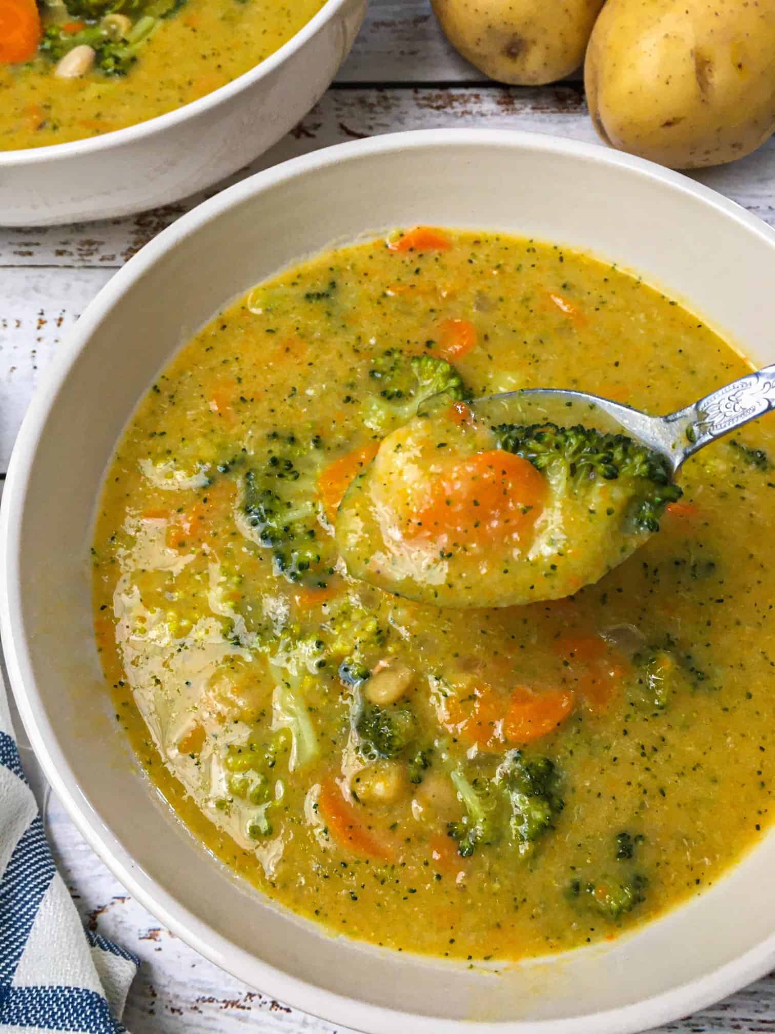spoon lifting up a bite of broccoli potato soup over bowl