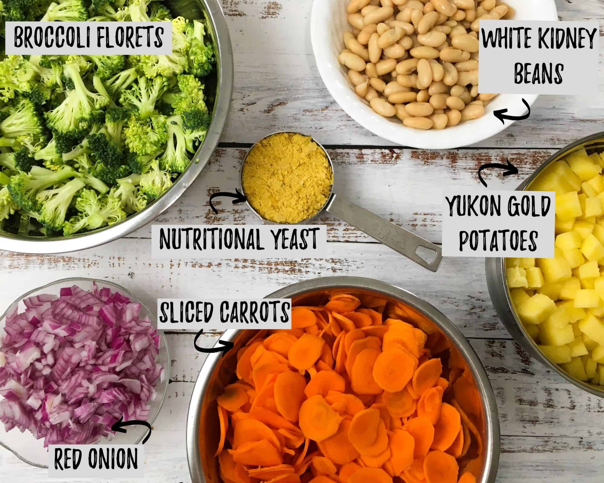 bowl of broccoli, bowl of red onion, bowl of sliced carrots, bowl of white beans and bowl of diced potatoes