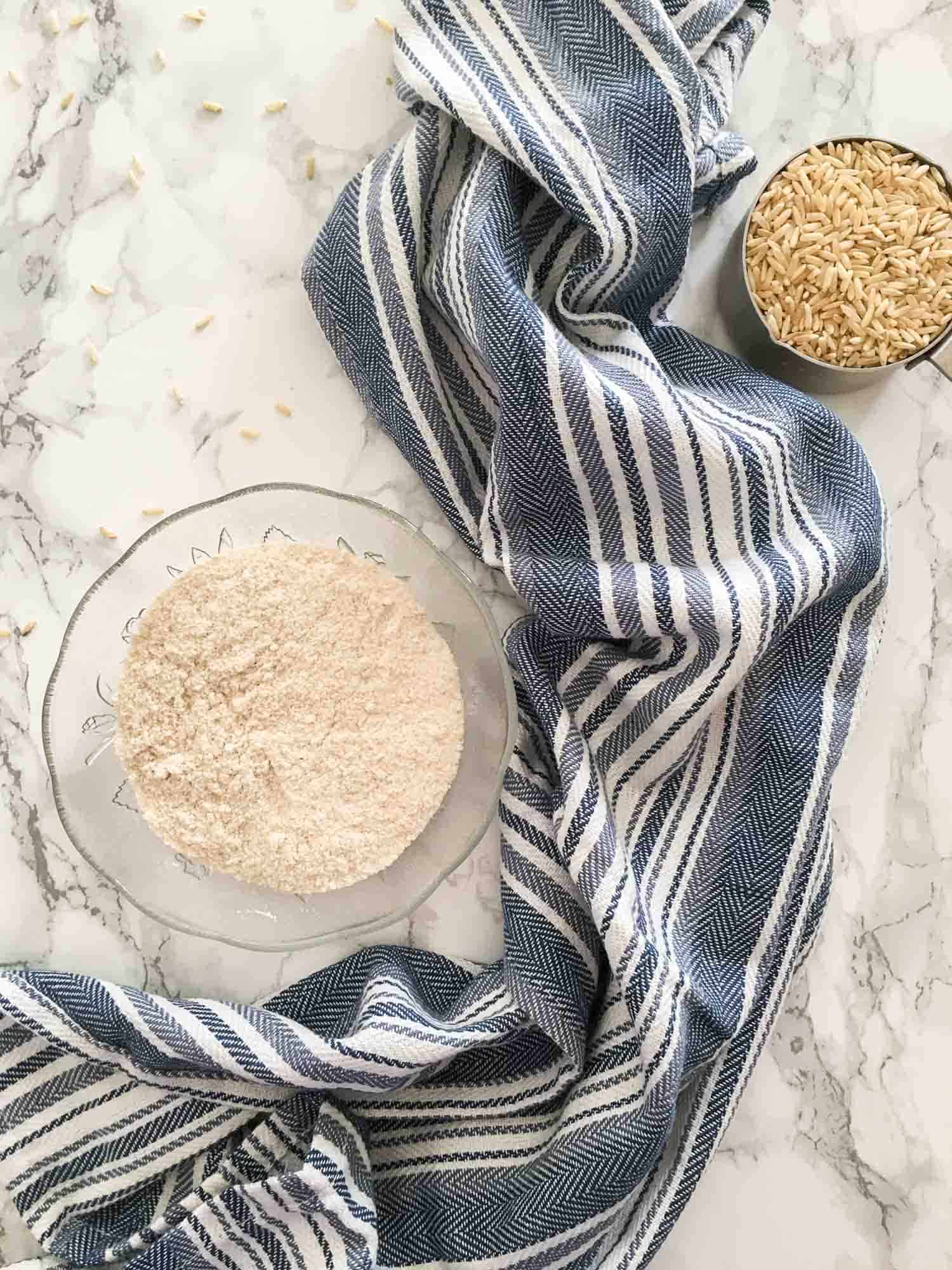 bowl of brown rice flour and cup of brown rice beside it