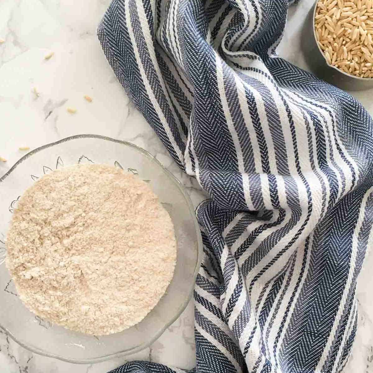 bowl of brown rice flour and cup of brown rice beside it