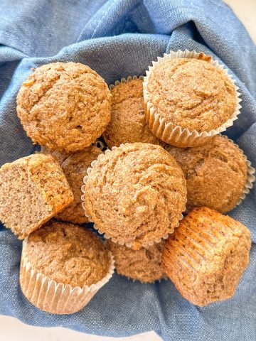 Buckwheat muffins in bowl with blue dish towel below it.