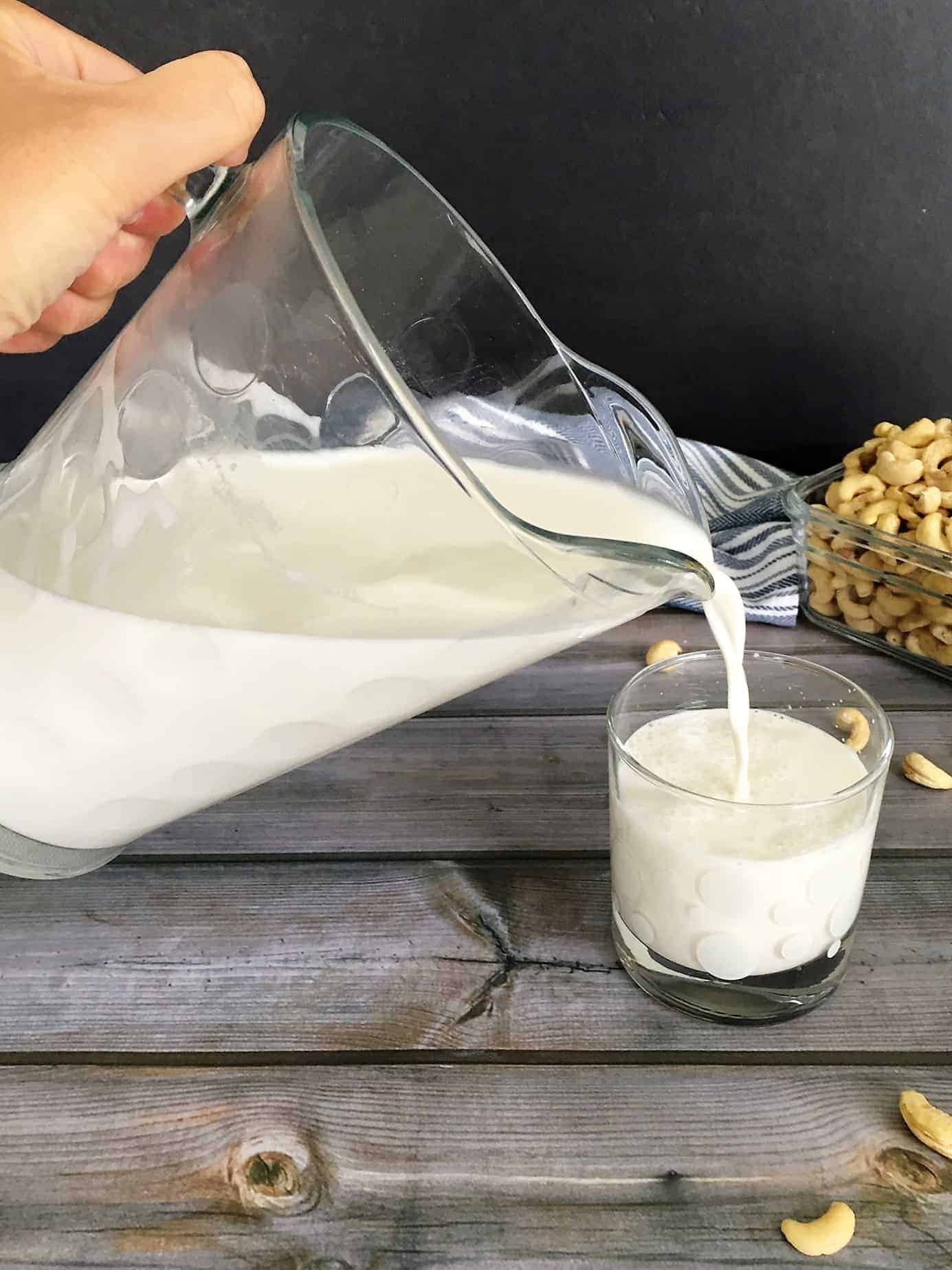cashew milk pouring from pitcher into glass
