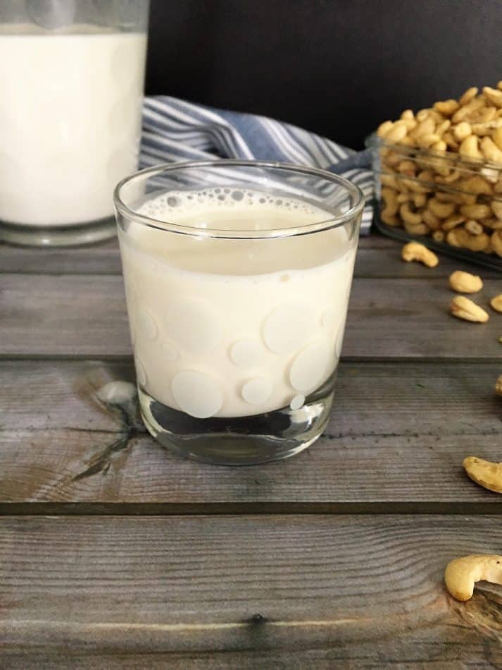 cashew milk in glass with picher in background