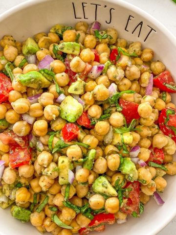 Chickpea avocado and tomato salad in white serving bowl.